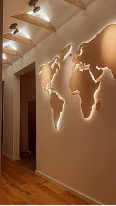 a world map on the wall in an empty room with wooden flooring and lighting