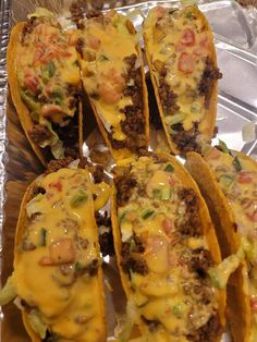 several tacos with cheese and other toppings sitting on tin foil