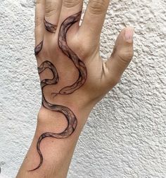 a person's hand with a black snake tattoo on the middle of their arm