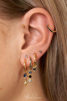 a close up of a person wearing three different colored ear piercings on their ears