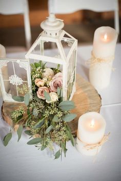 an arrangement of flowers and candles on a wooden slice at a wedding reception in white