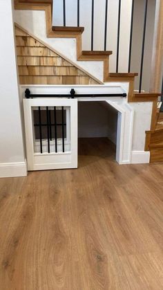 a dog house built into the side of a stair case in an empty room with wooden floors