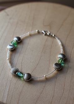 "Take your love of the beach to the next level with this stunning handmade, sea-inspired beaded bracelet.  Silver-toned metallic seashells frame glowing sea green glass beads, strung alongside crystal seeds and freshwater pearls.  This treasure is delicately yet securely fastened to your wrist with a dainty lobster claw clasp.  This luminous bracelet is 100% handmade by me. Each bead was specifically selected for perfection and threaded with nylon coated silver plated wire, ensuring excellent dr Glowing Sea, Seashell Frame, Handmade Beaded Bracelets, Beautiful Beaded Jewelry, Glass Beaded Bracelet, Vacation Accessories, Vacation Inspiration, Beach Getaway, Kawaii Accessories