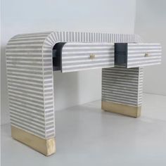 a white and gold desk sitting on top of a white floor next to a wall