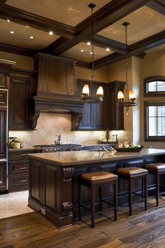 a large kitchen with wooden floors and dark wood cabinetry, along with two bar stools