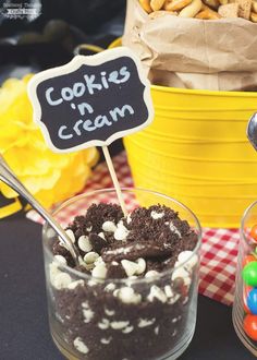 a table topped with two bowls filled with cake and candies next to a sign that says cookies'n cream