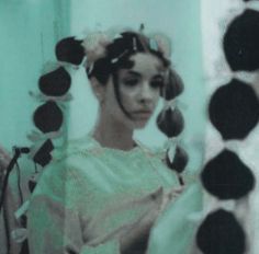 a woman is standing in front of a mirror with her hair pulled back and looking at the camera