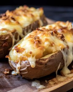 baked potatoes covered in cheese and toppings on a wooden cutting board, ready to be eaten