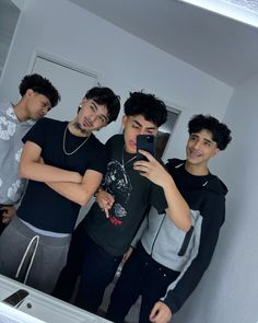 four young men are taking a selfie in the mirror