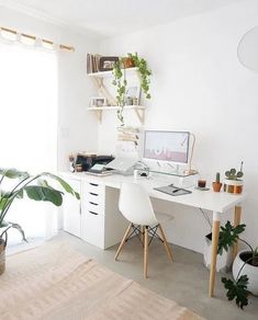 a white desk sitting in front of a window next to a potted plant on top of a wooden table