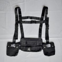 the back view of a black harness on a white sheeted bed with two pockets for suspenders