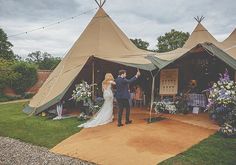 a bride and groom standing in front of a tippy - tipper wedding tent