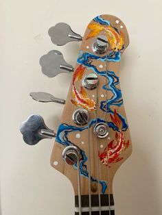 a close up of an electric guitar with colorful paint on it's body and strings