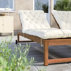 two white chaise lounge chairs sitting on top of a stone floor next to plants