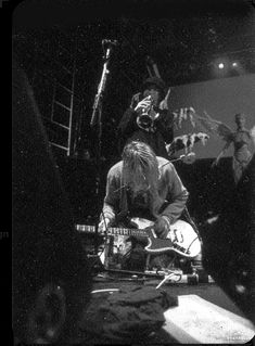 black and white photograph of man playing guitar on stage