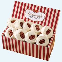 a red and white box filled with cupcakes covered in frosting and pecans