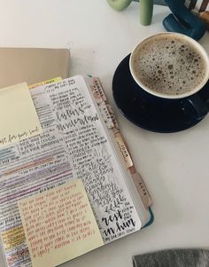 a cup of coffee sitting on top of a table next to an open notebook and pen