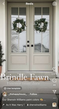 the front door is decorated with wreaths and two potted plants on top of it