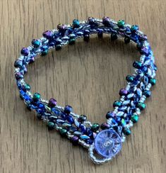 the beaded bracelet has a button on it and is decorated with blue, green and white beads