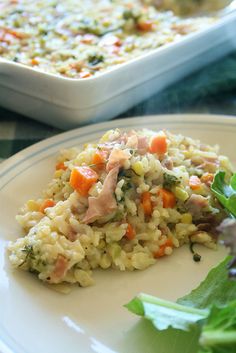 a white plate topped with rice covered in meat and veggies next to a casserole dish