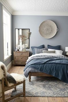 a bedroom with blue walls and wooden floors, a bed in the middle is surrounded by pillows