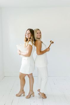 two women standing next to each other in white outfits