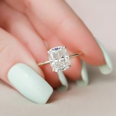 a woman's hand holding a ring with a large diamond in the middle of it