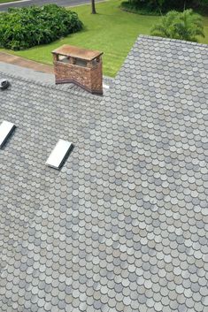 an aerial view of a roof with two air vents on it and a brick chimney in the background