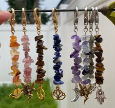 several different colored beads hanging from hooks in front of a white fence and green grass