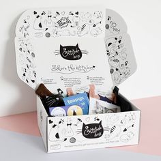 an open box with various items inside on a pink and white surface