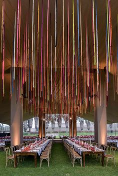 a large tent with many tables and chairs set up for a party or function in the grass