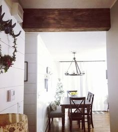 a dining room table and chairs in front of a white wall with wood planks