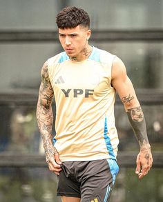 a man with tattoos on his arm and leg is standing in front of a soccer ball