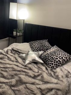 a bed with two pillows on top of it next to a night stand and lamp