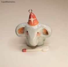 an elephant figurine with a party hat on it's head sitting next to a toothbrush