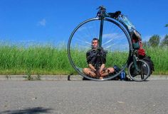 a man sitting on the ground next to a bike with his legs crossed in front of him