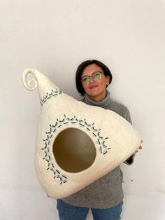 a woman is holding a large white vase