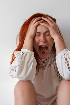 a woman with red hair is holding her hands up to her face and covering her eyes