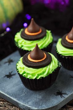 three halloween cupcakes with green frosting and witch hats on top