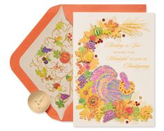 an orange and white greeting card with a turkey on it, surrounded by autumn flowers