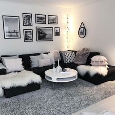 a living room with black and white furniture, pictures on the wall and rugs