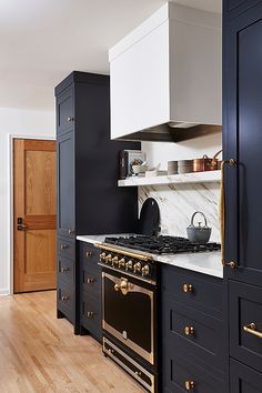 a kitchen with black cabinets and gold accents