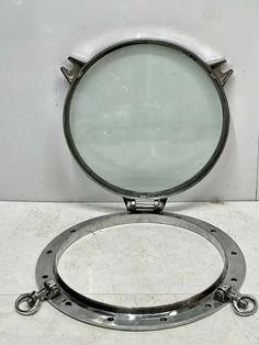 a round mirror sitting on top of a white counter next to a metal object with chains around it