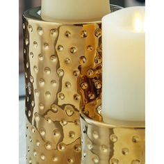 two gold candle holders sitting next to each other on top of a white countertop