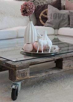 a coffee table made from an old pallet with glass top and wheels on the bottom