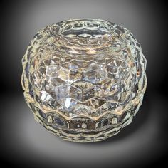 a clear glass bowl sitting on top of a black table next to a gray wall