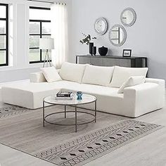 a living room with white furniture and large windows on the wall, including a sectional sofa