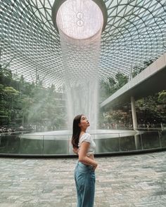 a woman is standing in front of a fountain at the gardens by the bay, singapore