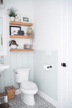 a white toilet sitting in a bathroom next to a wooden shelf filled with potted plants