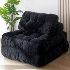 a black recliner sitting on top of a hard wood floor next to a green plant